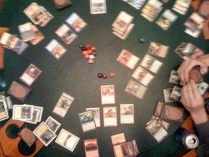 Magic; The Gathering game in progress with cards and dice on a tabletop